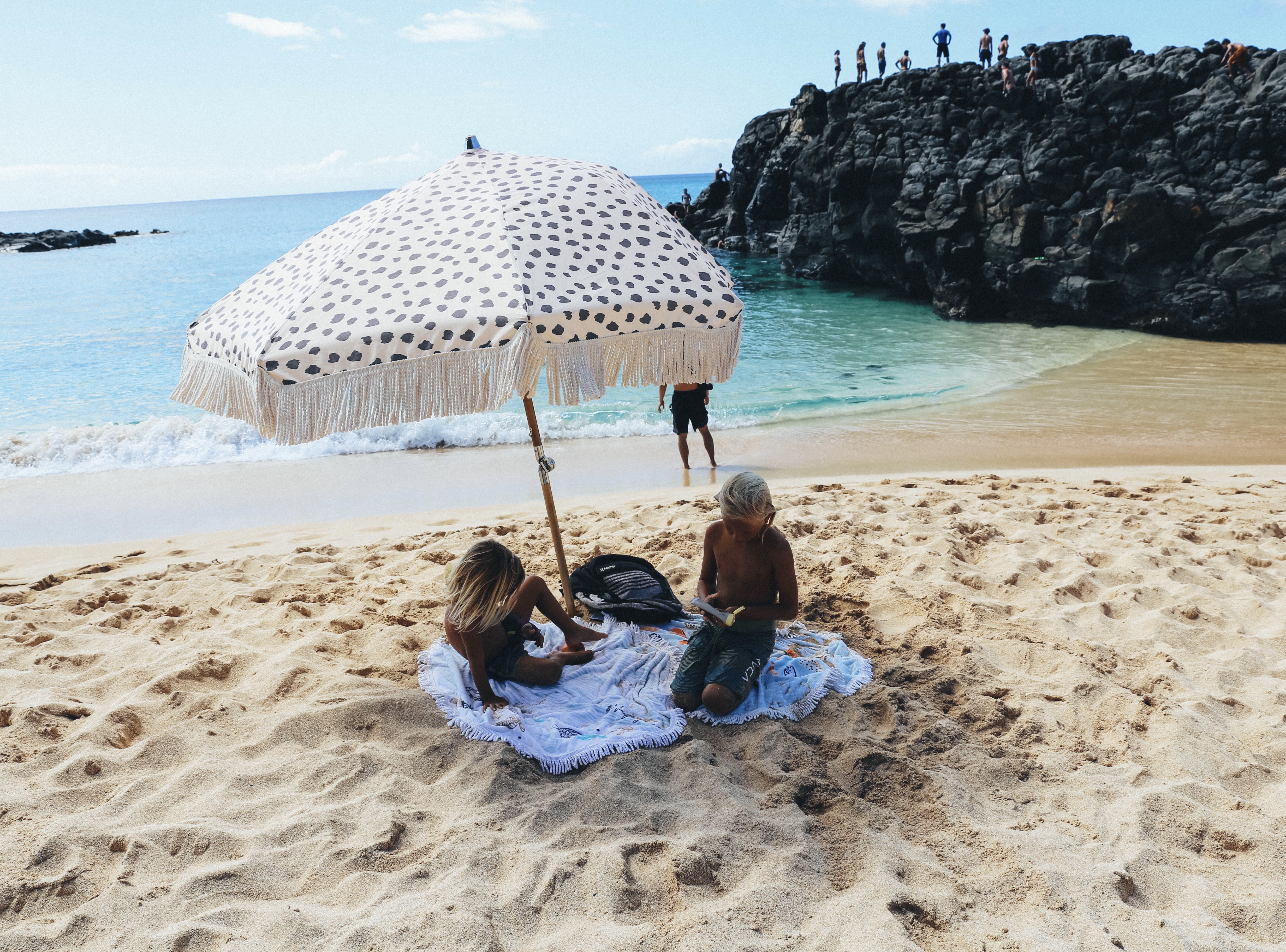 kids sitting under umbrella on beach