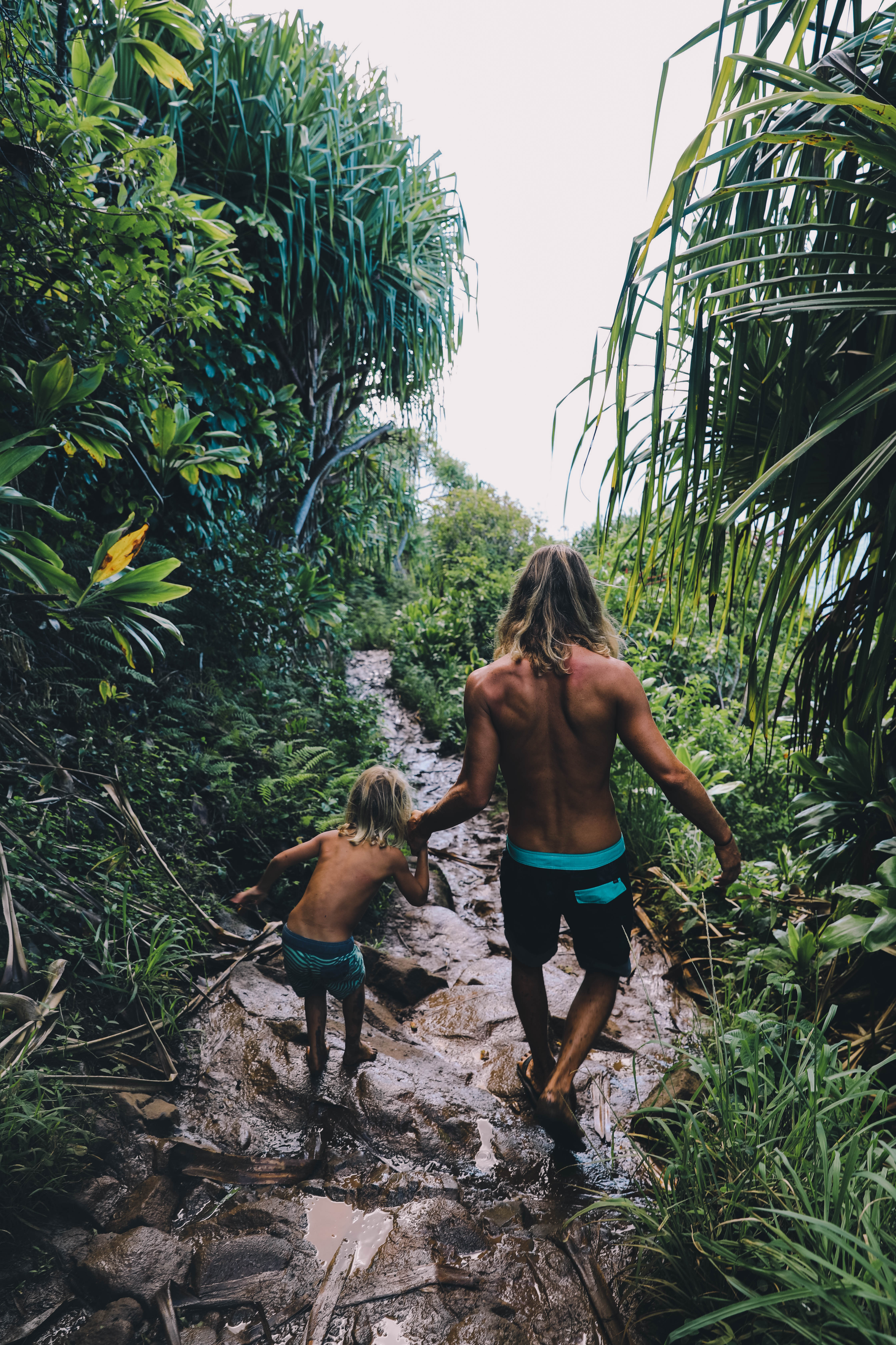 dad and son hiking on muddy jungle trail