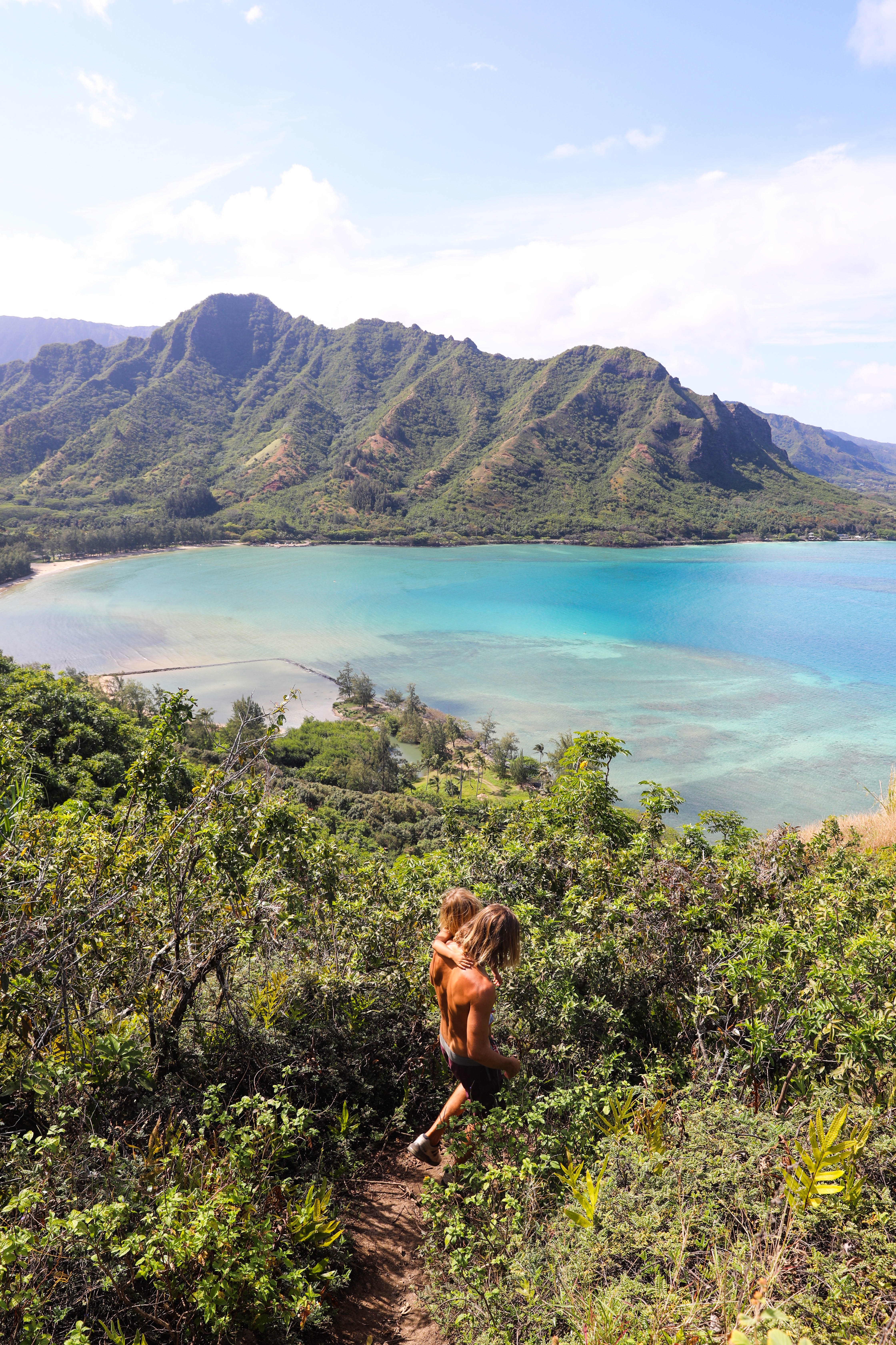 dad and son walking down rocky path overlooking beach