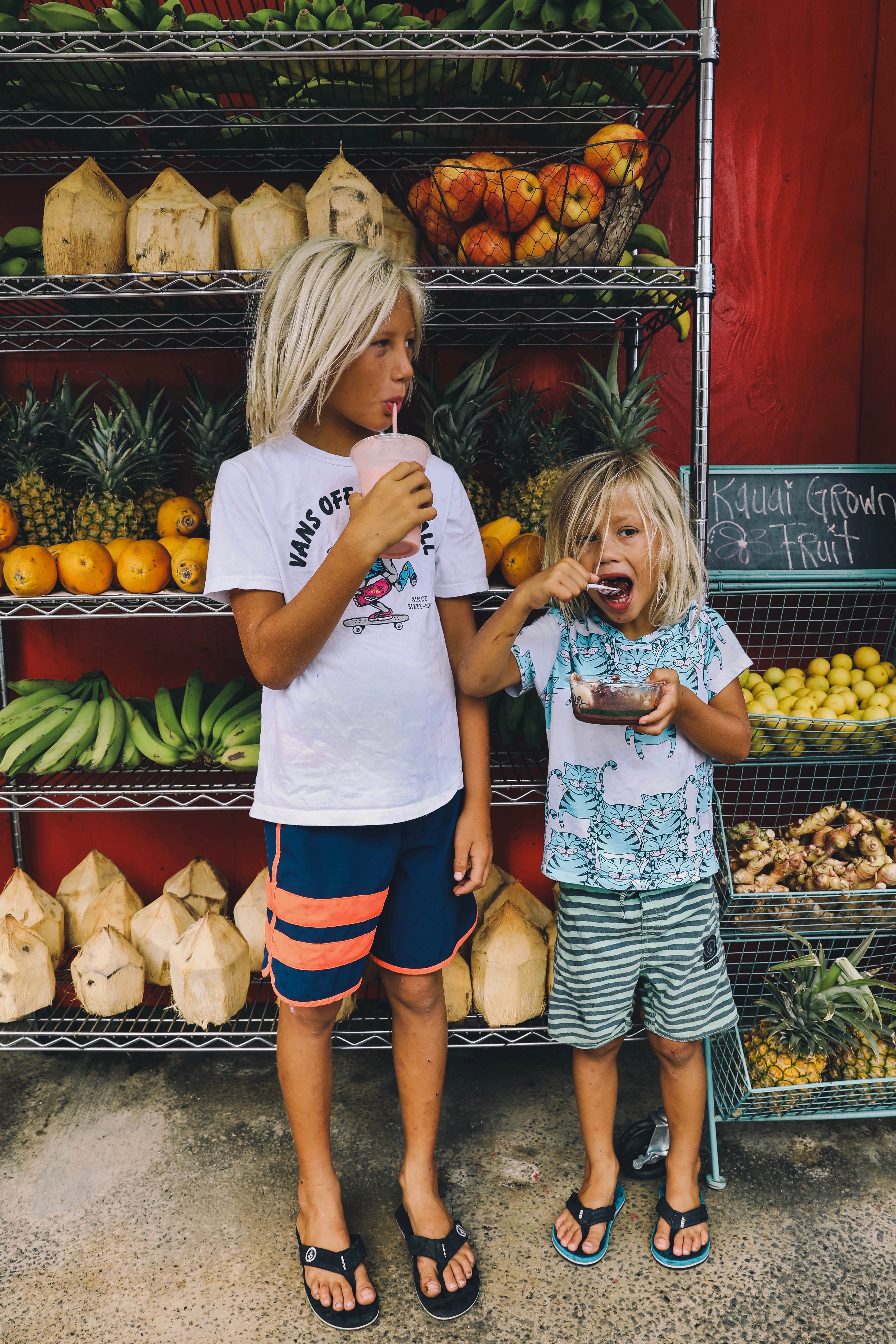 kids snacking in front of fruit stand