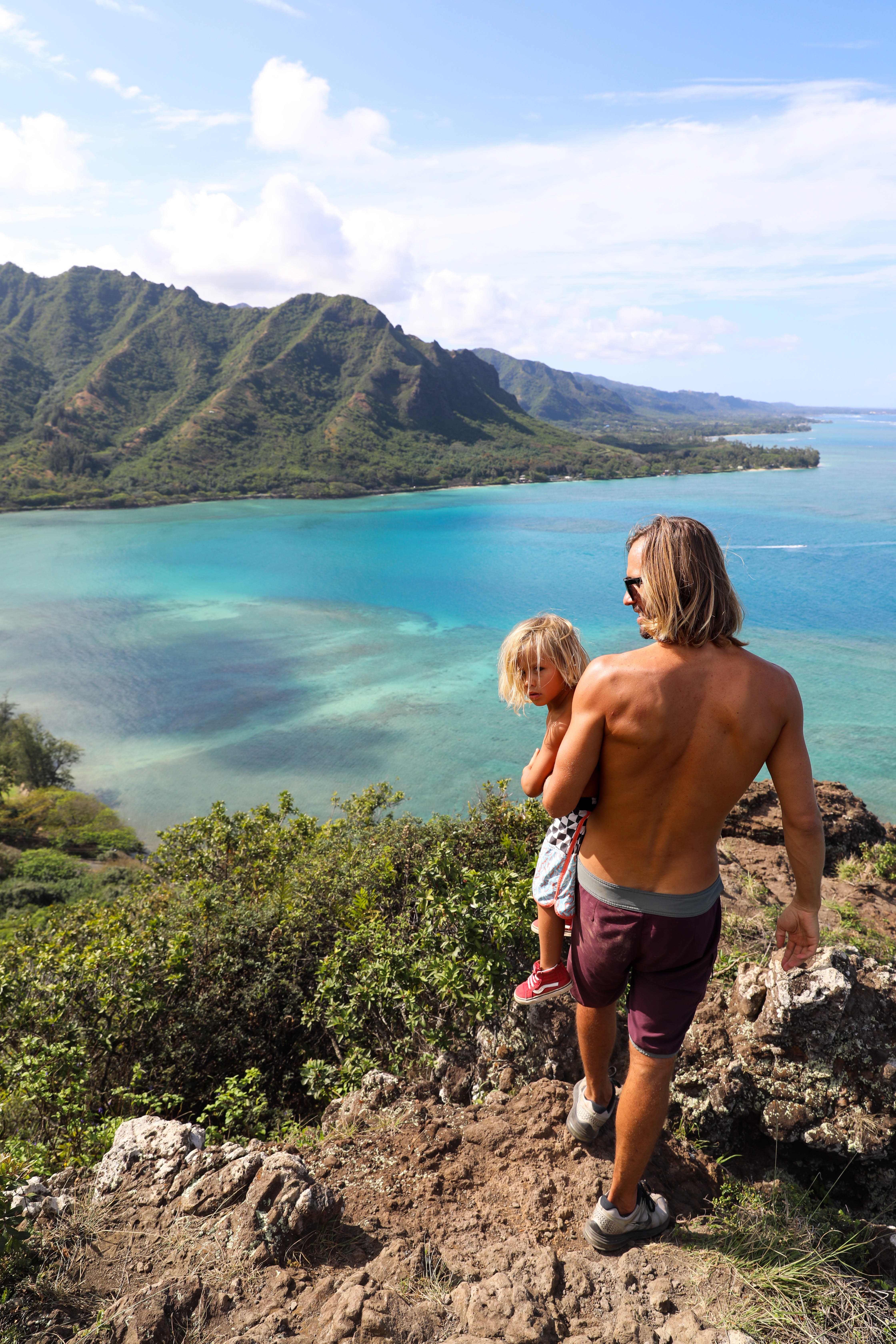 dad and son hiking rocky cliff overlooking beach
